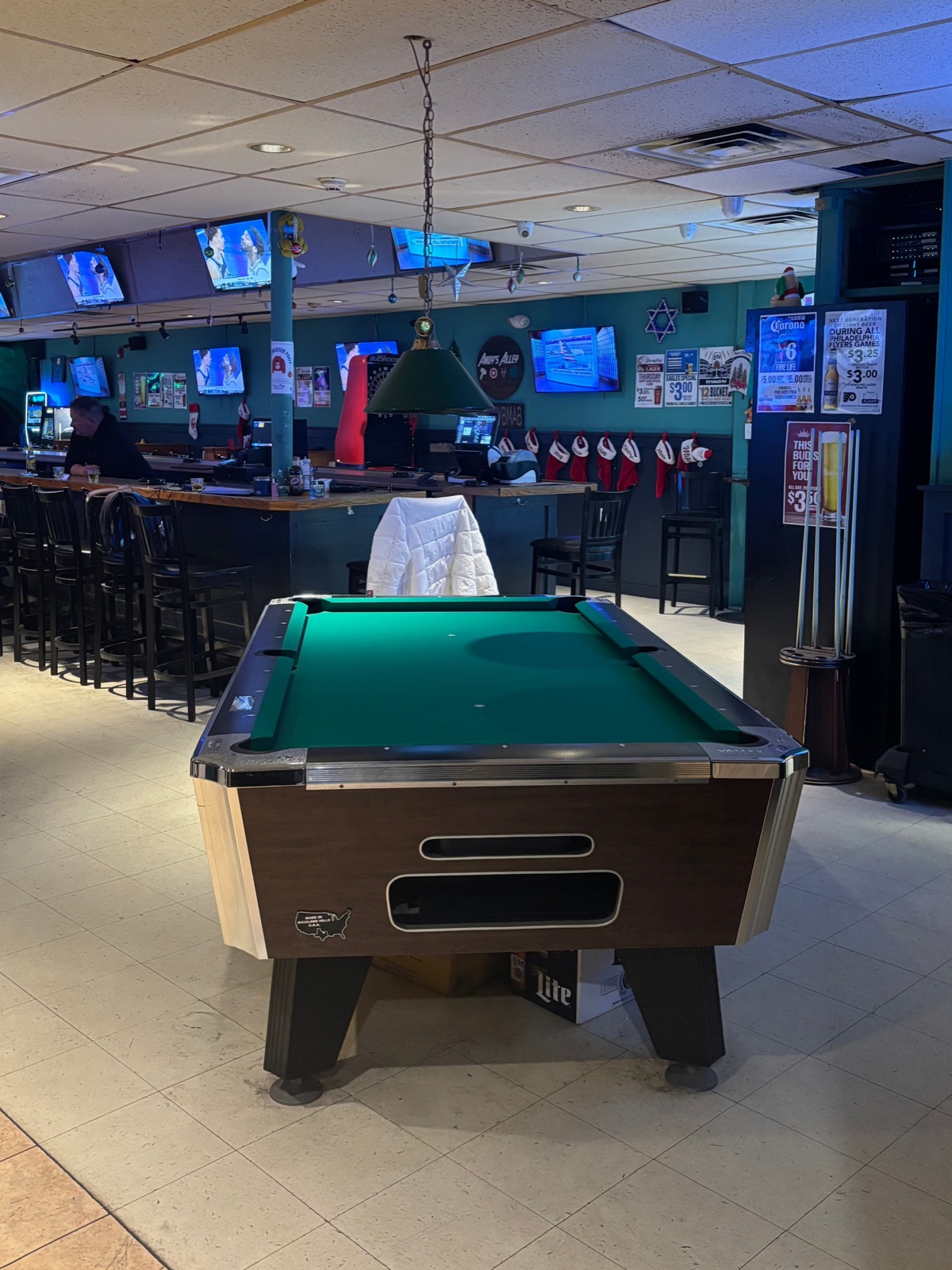 Pike's Pub pool table with bar and TVs behind